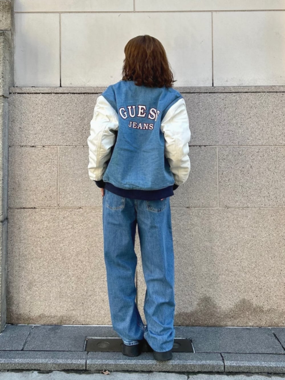 ブルー系のデニムパンツ、ブルー系のスタジャン、ホワイト系のニット/セーターを着用したレディースの冬コーディネートの2枚目の写真