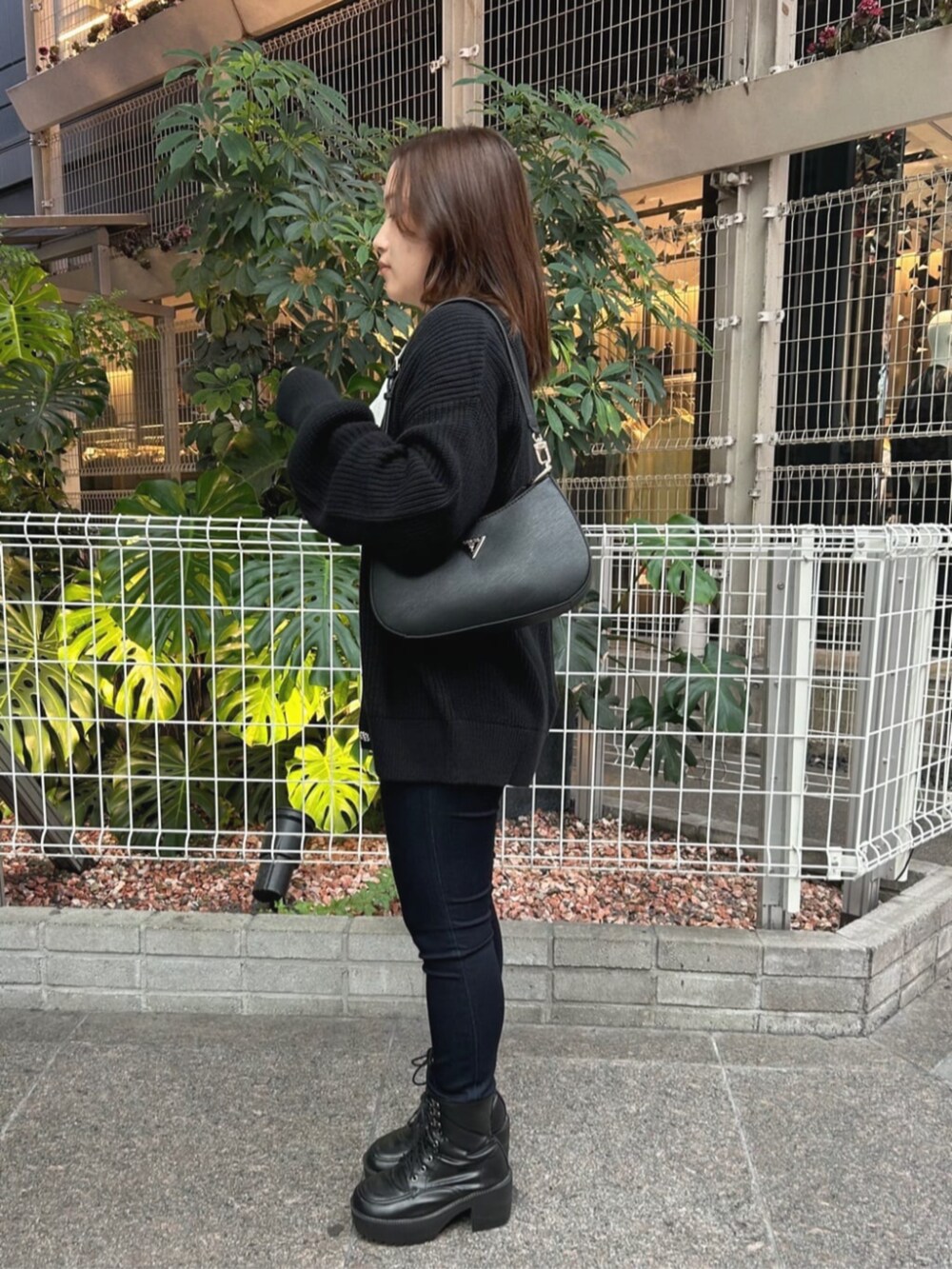 ブラック系のショルダーバッグ、ブルー系のデニムパンツ、ブラック系のカーディガン/ボレロを着用したレディースの秋コーディネートの3枚目の写真