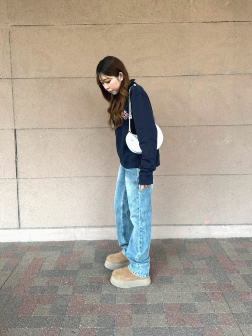 ブルー系のデニムパンツ、ホワイト系のハンドバッグ、ブルー系のスウェットを着用したレディースの冬コーディネートの5枚目の写真