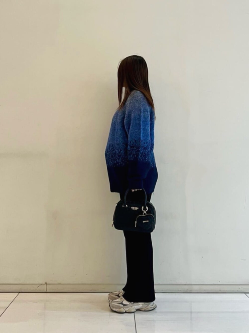 ブラック系のハンドバッグ、ブルー系のポロシャツ、ブルー系のニット/セーターを着用したレディースの冬コーディネートの3枚目の写真