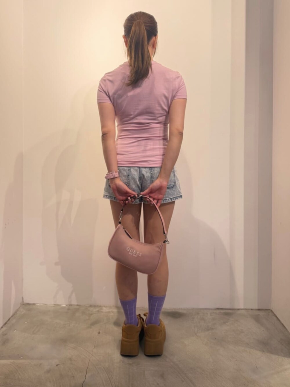 ブルー系のデニムパンツ、ピンク系のショルダーバッグ、ピンク系のTシャツ/カットソーを着用したレディースの冬コーディネートの2枚目の写真