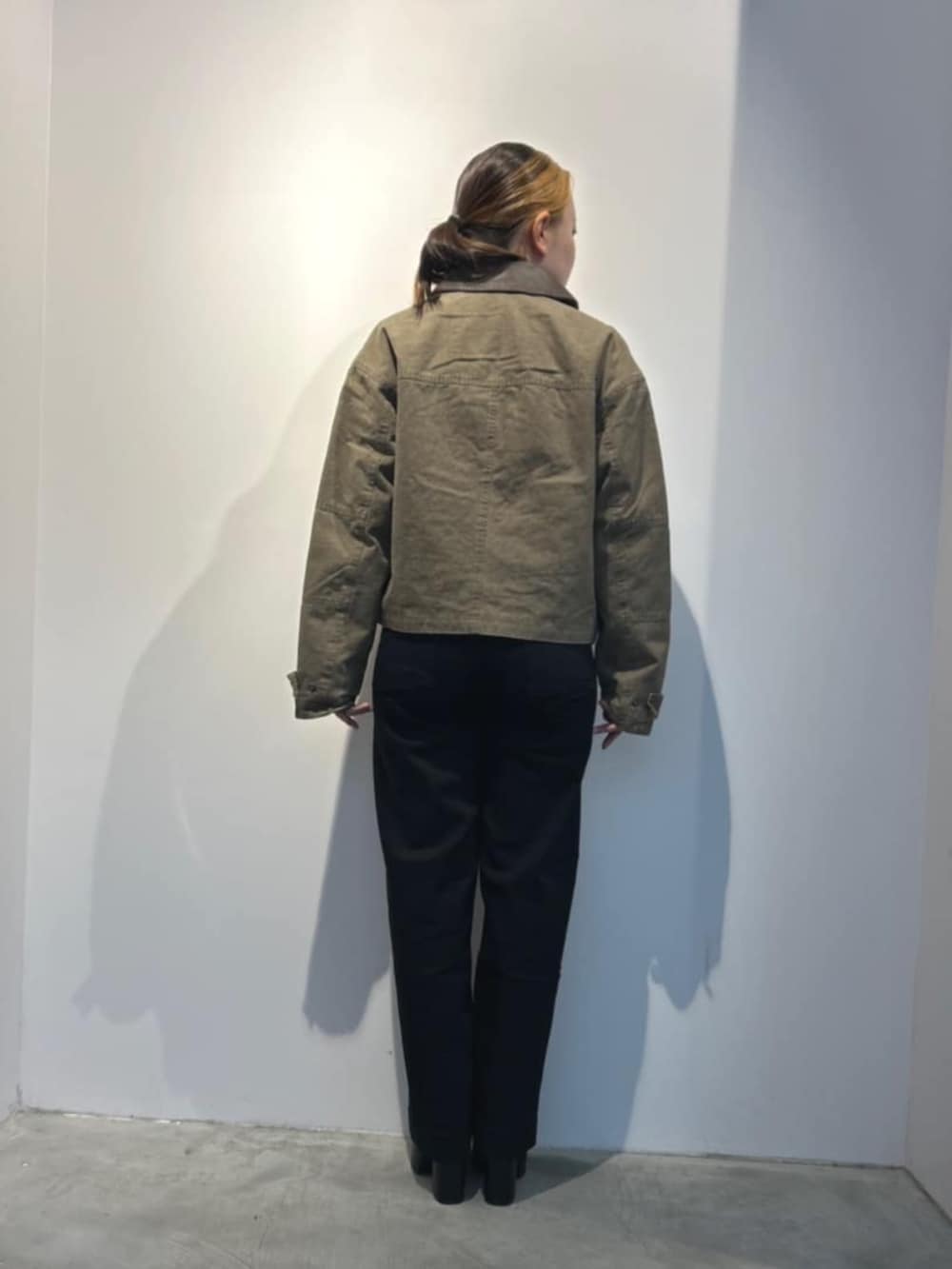 ブラック系のデニムパンツ、ブラック系のTシャツ/カットソー、グリーン系のミリタリージャケットを着用したレディースの春コーディネートの3枚目の写真