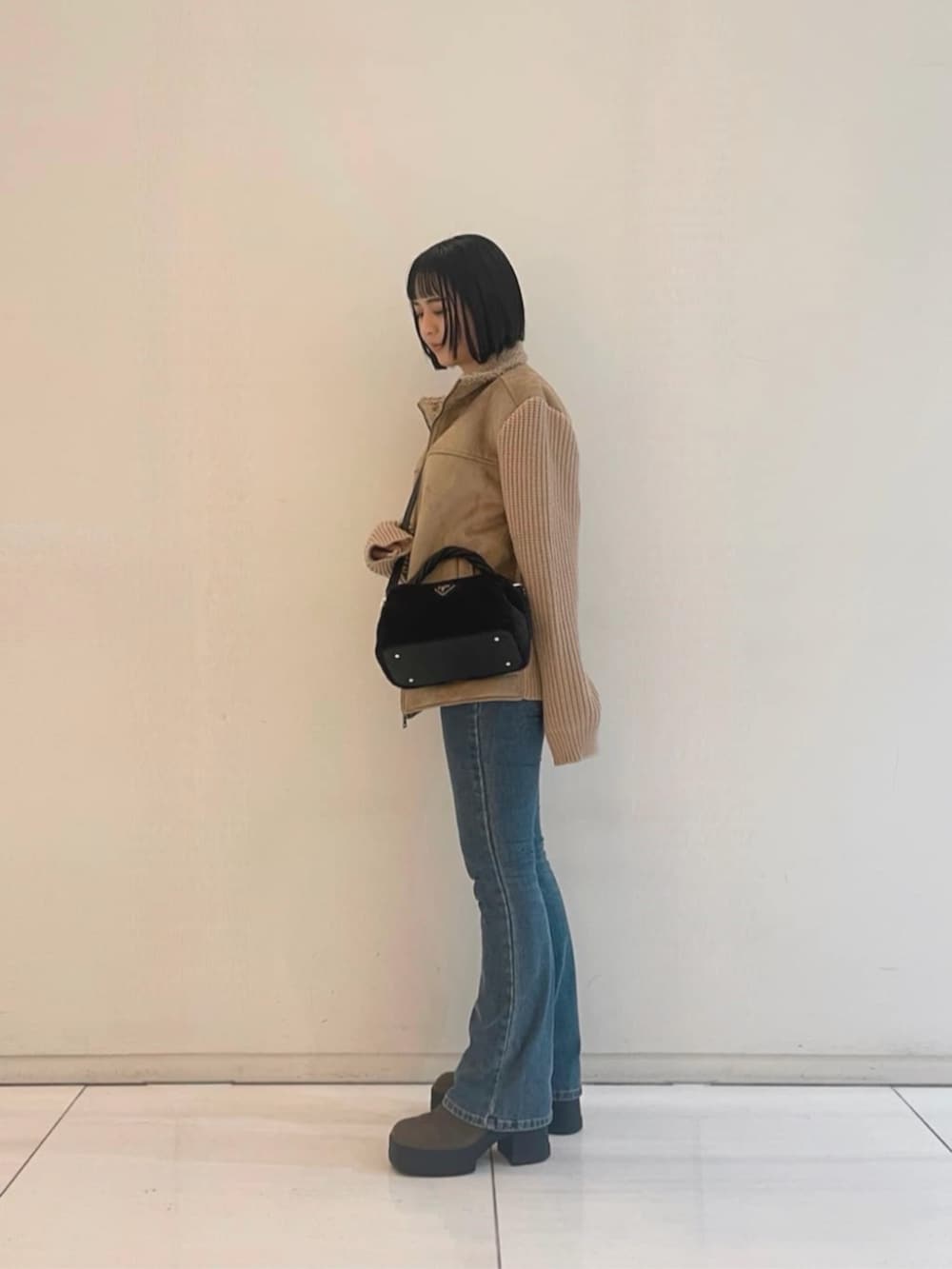 ブルー系のデニムパンツ、ブラック系のニット/セーター、ブラック系のショルダーバッグを着用したレディースの冬コーディネートの3枚目の写真