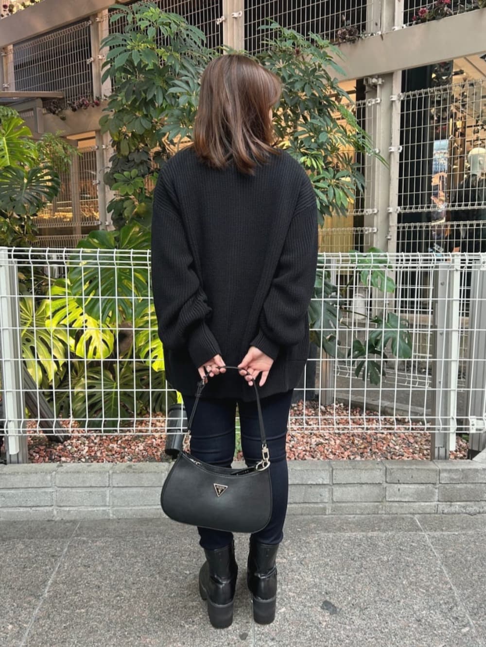 ブラック系のショルダーバッグ、ブルー系のデニムパンツ、ブラック系のカーディガン/ボレロを着用したレディースの秋コーディネートの2枚目の写真