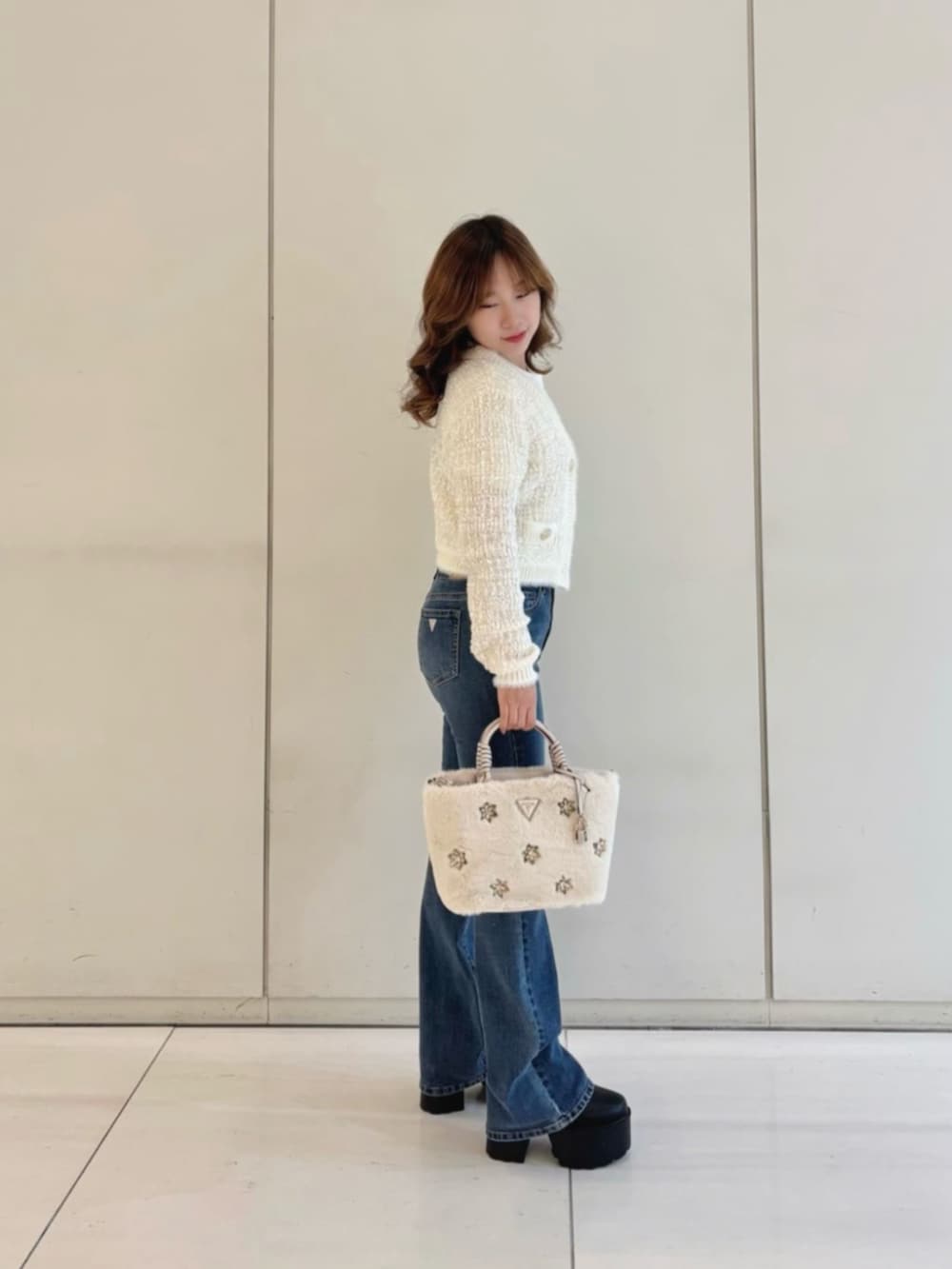 ブルー系のデニムパンツ、ホワイト系のショルダーバッグ、ホワイト系のカーディガン/ボレロを着用したレディースの冬コーディネートの3枚目の写真