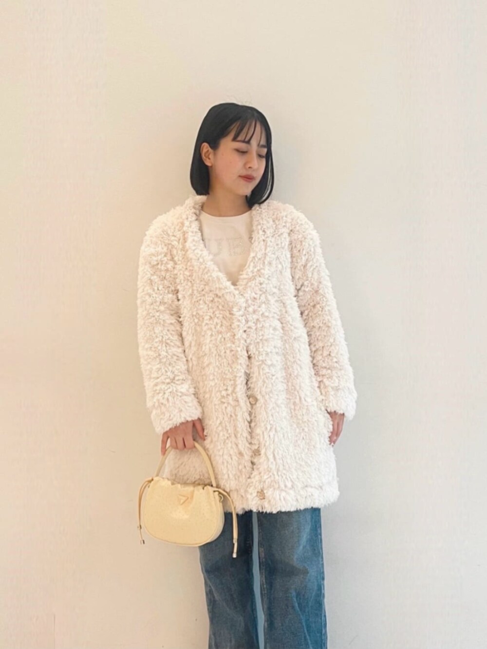 ブルー系のデニムパンツ、ホワイト系のカーディガン/ボレロ、ホワイト系のTシャツ/カットソーを着用したレディースの冬コーディネートの4枚目の写真