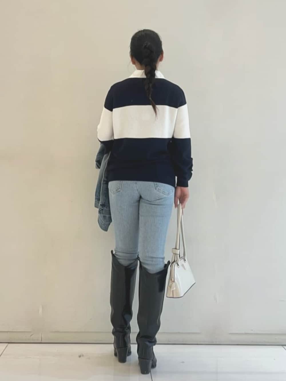 ホワイト系のショルダーバッグ、ブルー系のポロシャツ、ブルー系のデニムパンツを着用したレディースの春コーディネートの2枚目の写真