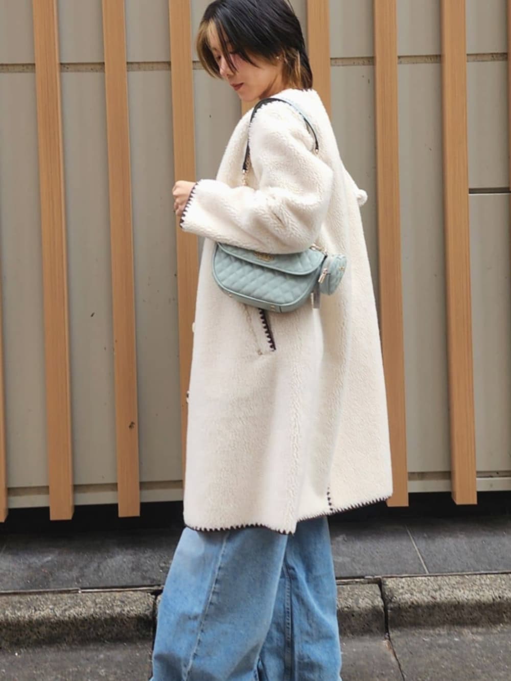 ホワイト系のタンクトップ、ブルー系のデニムパンツ、ホワイト系のノーカラージャケットを着用したレディースの冬コーディネートの6枚目の写真