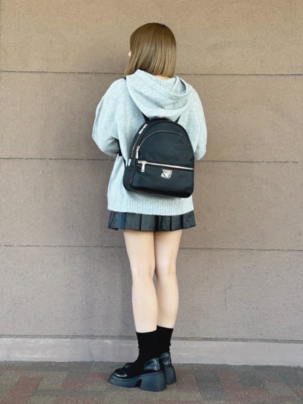 ブラック系のスカート、グレー系のパーカー、ブラック系のバックパック/リュックを着用したレディースの冬コーディネートの3枚目の写真