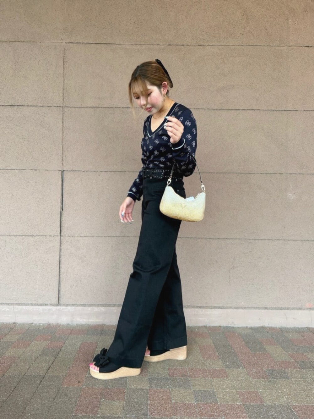 ブラック系のデニムパンツ、ブルー系のニット/セーター、ゴールド系のハンドバッグを着用したレディースの秋コーディネートの3枚目の写真