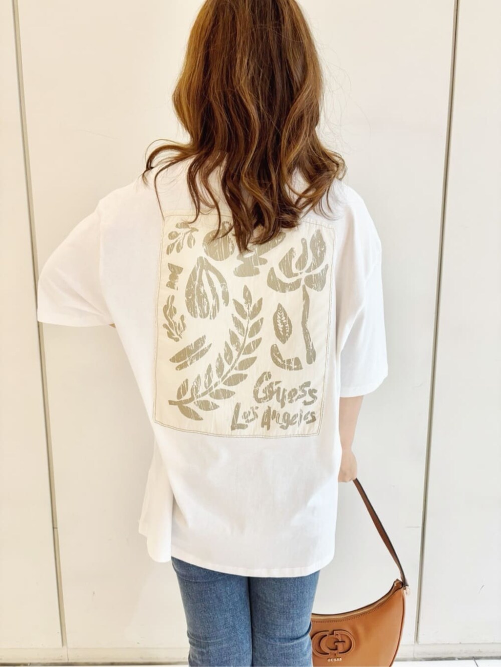 ブルー系のデニムパンツ、ホワイト系のシャツ/ブラウス、ブラウン系のショルダーバッグを着用したレディースの秋コーディネートの4枚目の写真