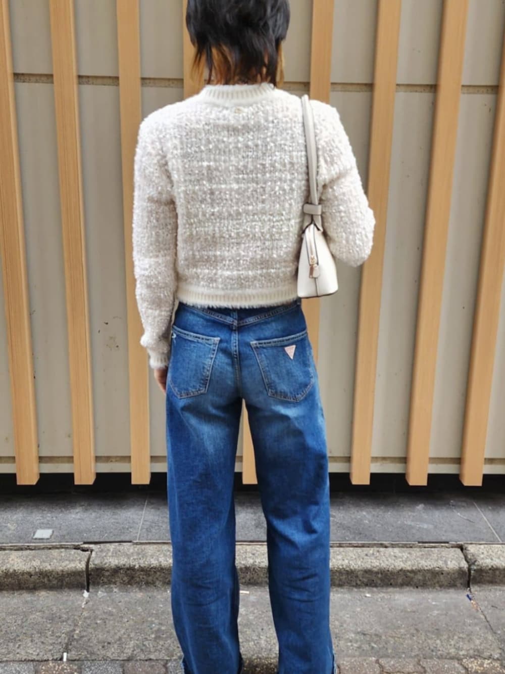 ホワイト系のショルダーバッグ、ブルー系のデニムパンツ、ホワイト系のカーディガン/ボレロを着用したレディースの冬コーディネートの2枚目の写真