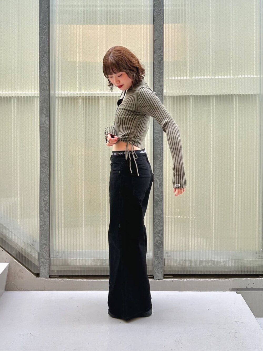 ブラック系のデニムパンツ、グリーン系のカーディガン/ボレロ、ブラック系のボクサーパンツを着用したレディースの秋コーディネートの3枚目の写真