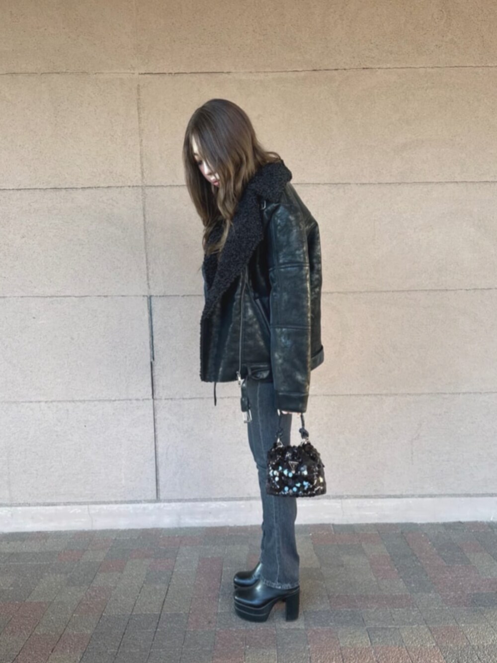 ブラック系のライダースジャケット、ブラック系のショルダーバッグ、ブラック系のデニムパンツを着用したレディースの冬コーディネートの3枚目の写真