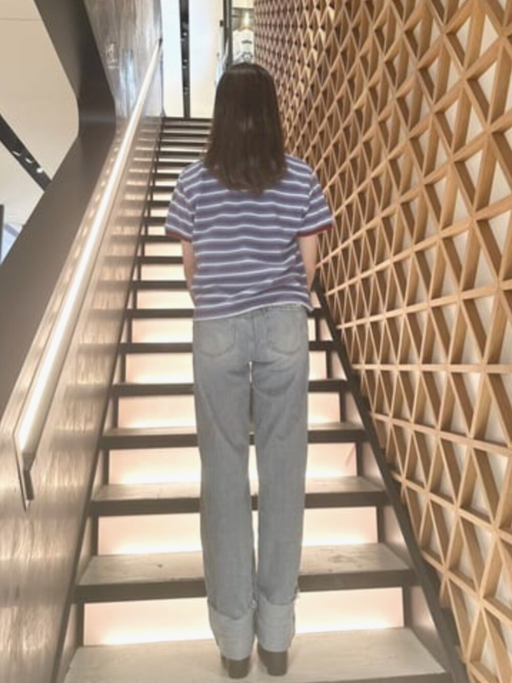 ブルー系のデニムパンツ、ブルー系のポロシャツ、ベージュ系のショルダーバッグを着用したレディースの夏コーディネートの2枚目の写真