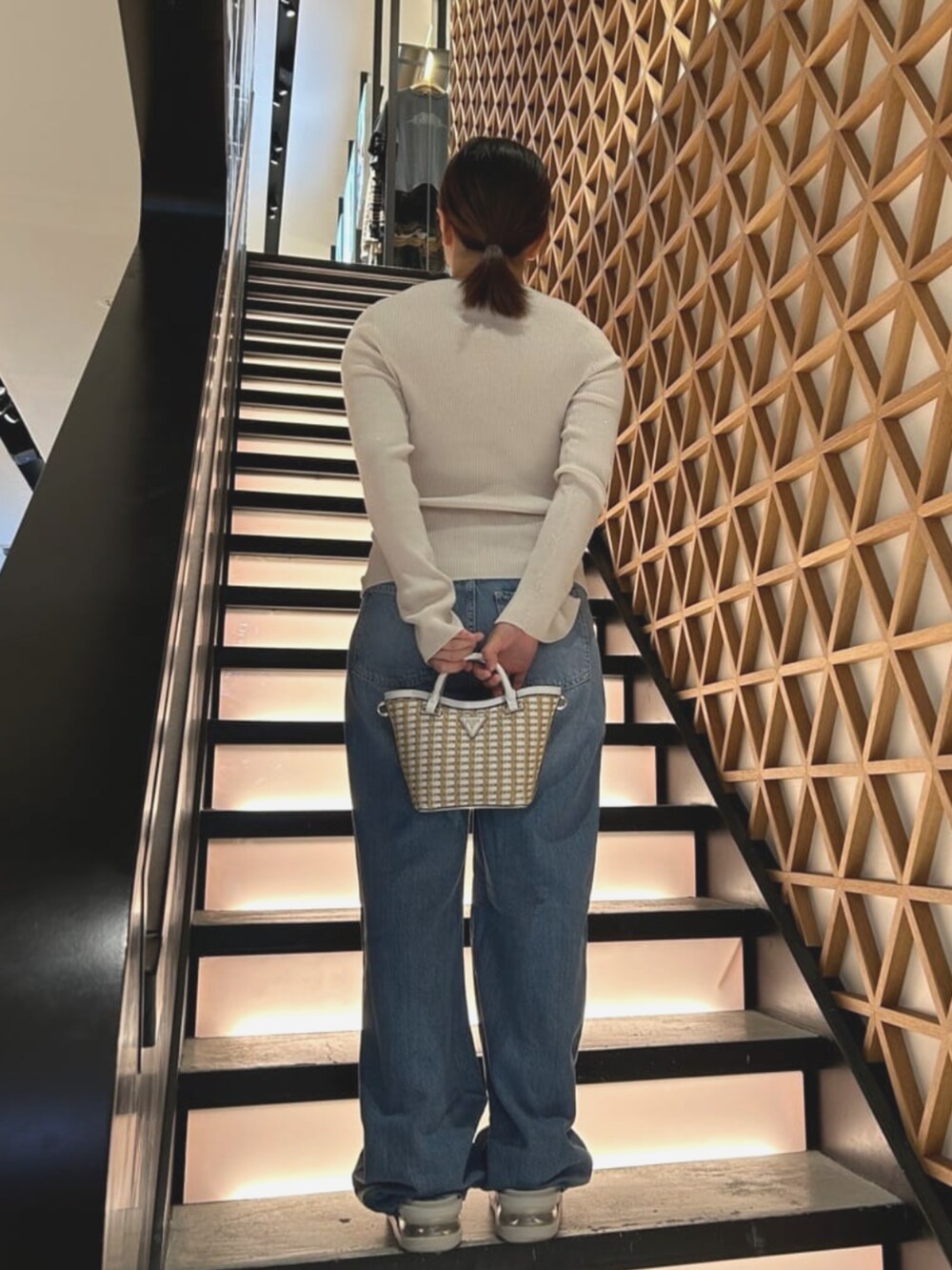 ホワイト系のショルダーバッグ、ブルー系のデニムパンツ、ホワイト系のニット/セーターを着用したレディースの夏コーディネートの2枚目の写真