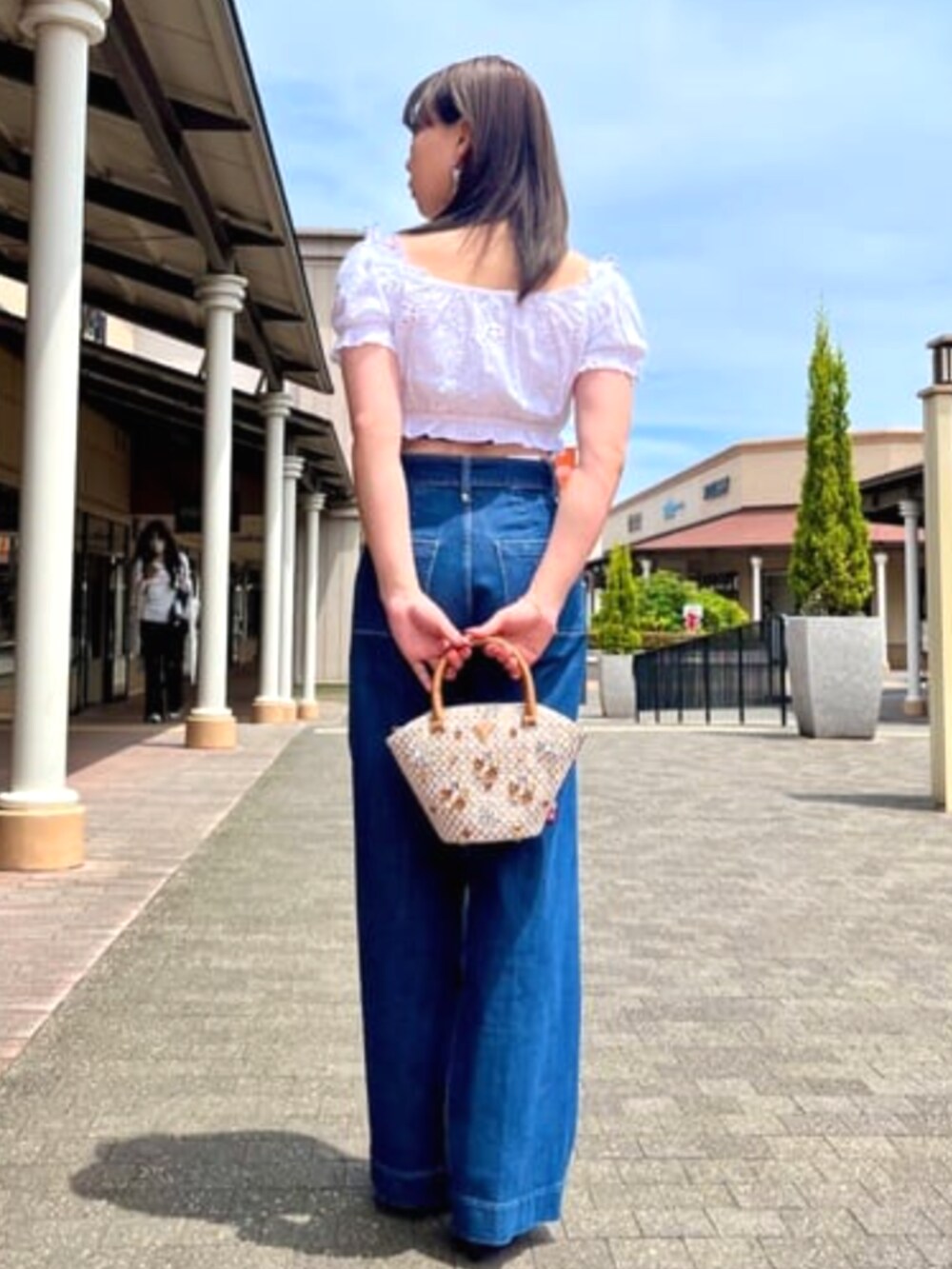 ブルー系のデニムパンツ、ブラウン系のショルダーバッグを着用したレディースの夏コーディネートの2枚目の写真