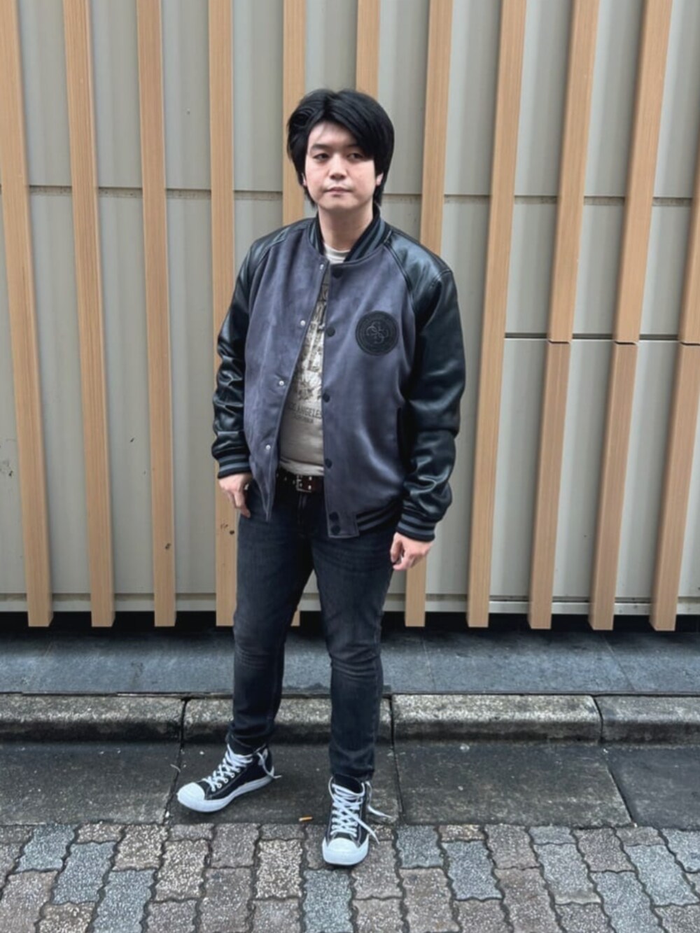 ベージュ系のTシャツ/カットソー、グレー系のスタジャン、グレー系のデニムパンツを着用したメンズの秋コーディネートの4枚目の写真