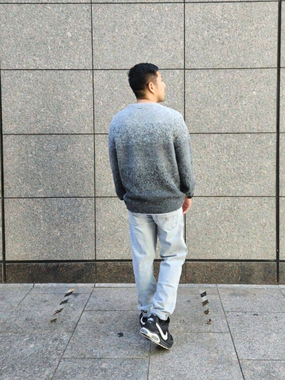 グレー系のデニムパンツ、グレー系のニット/セーター、シルバー系のネックレスを着用したメンズの秋コーディネートの2枚目の写真