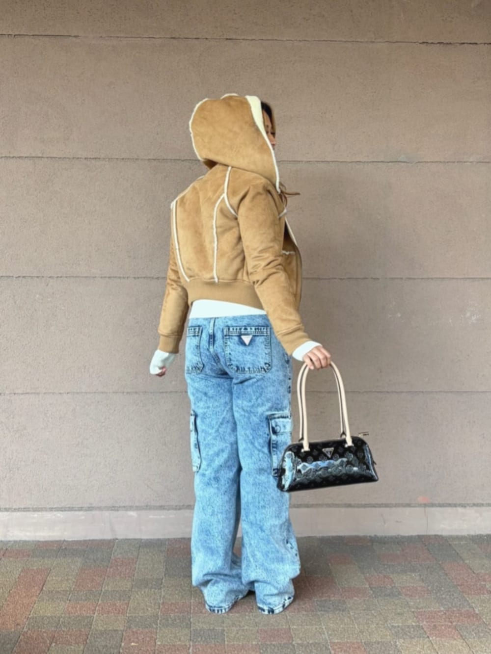 ベージュ系のパーカー、ブラック系のショルダーバッグ、ホワイト系のニット/セーターを着用したレディースの冬コーディネートの2枚目の写真