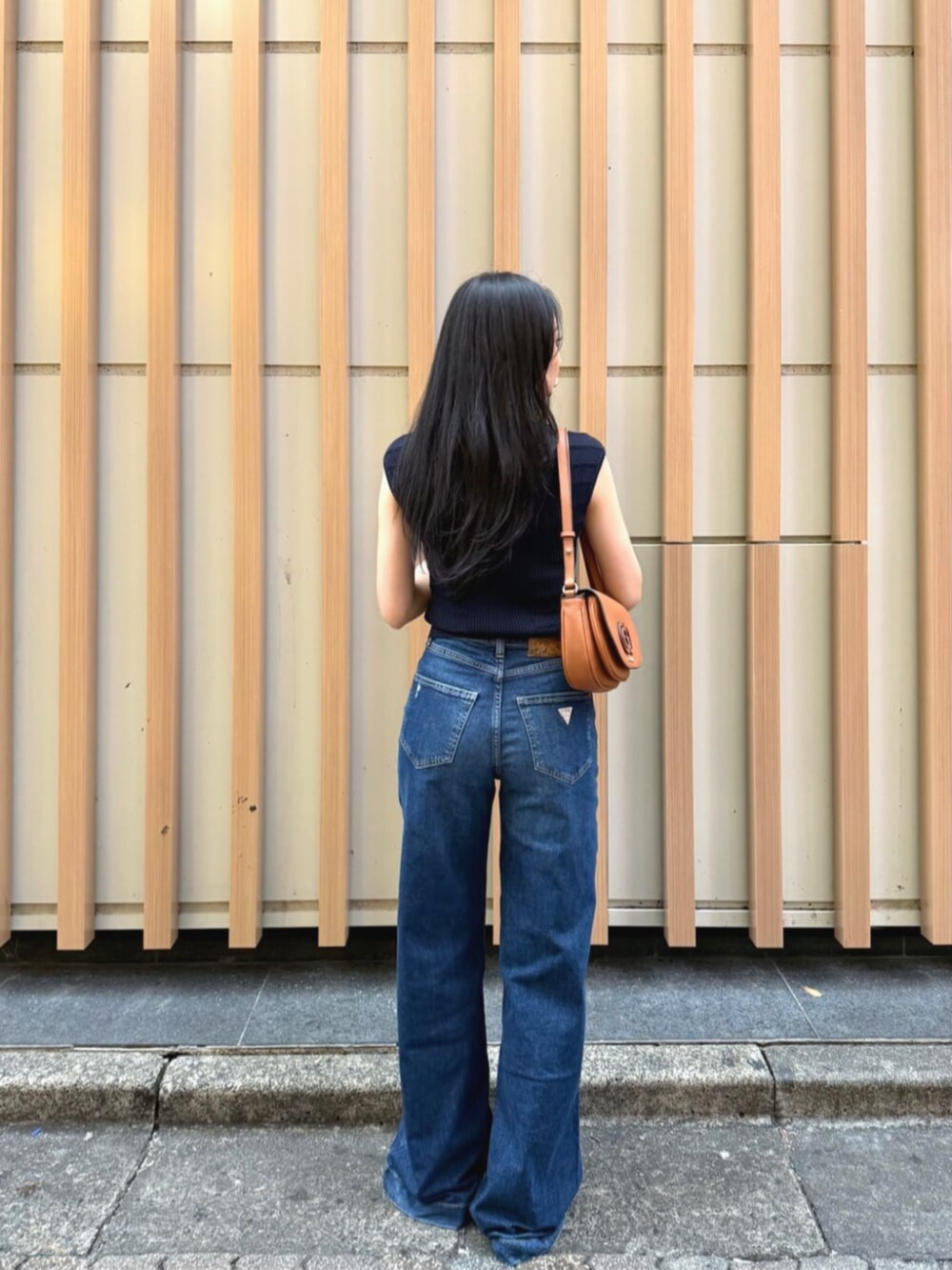 ブルー系のデニムパンツ、ブルー系のタンクトップ、ブラウン系のショルダーバッグを着用したレディースの秋コーディネートの2枚目の写真