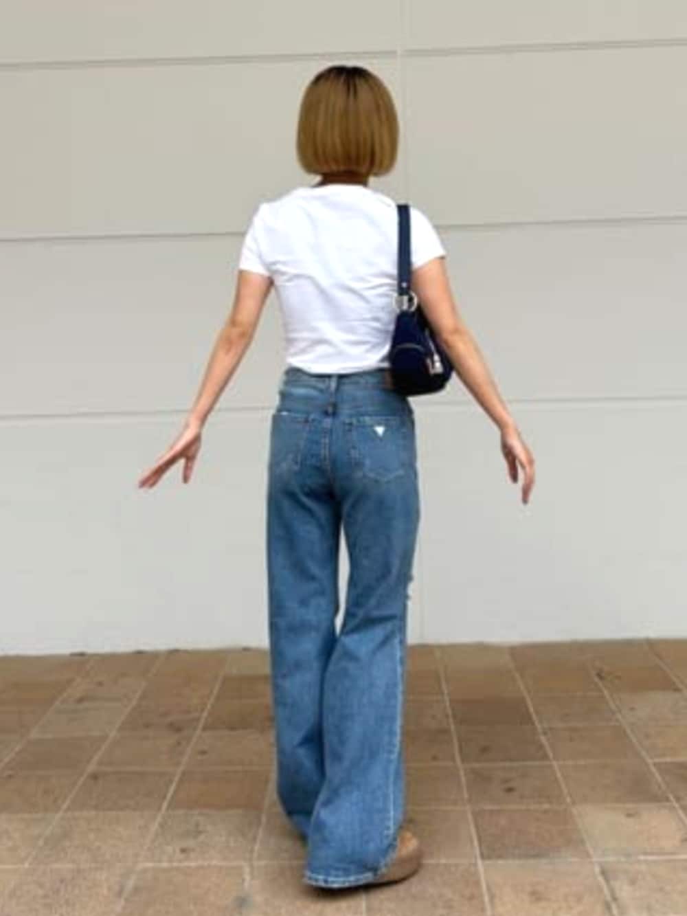 ブルー系のデニムパンツ、ブルー系のハンドバッグを着用したレディースの夏コーディネートの2枚目の写真