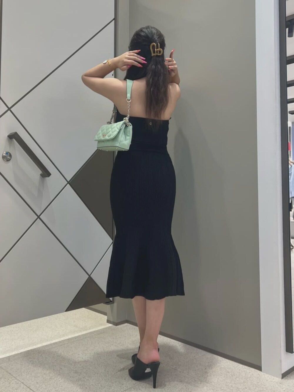 グリーン系のショルダーバッグ、ブラック系のワンピース、ホワイト系のブレスレットを着用したレディースの夏コーディネートの2枚目の写真