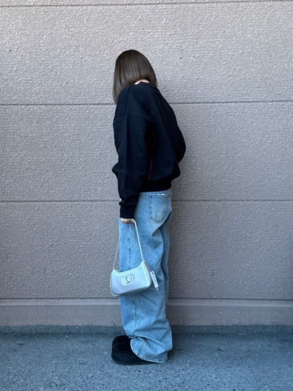 ブラック系のスウェット、ブルー系のデニムパンツを着用したレディースの春コーディネートの5枚目の写真