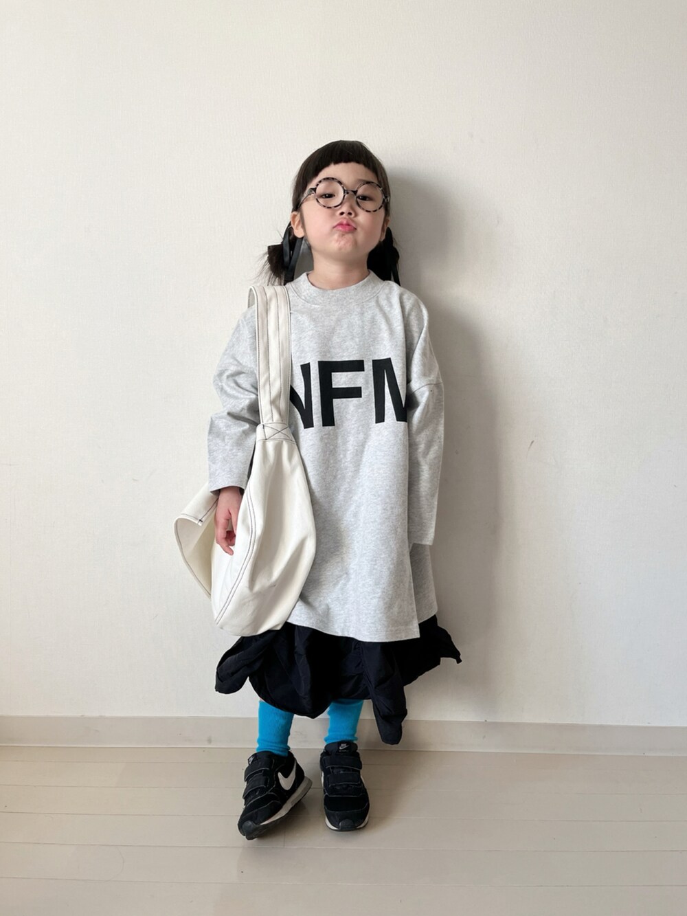 ホワイト系のワンピース、ブラック系のスカート、ブラック系のスニーカーを着用したキッズの冬コーディネートの3枚目の写真