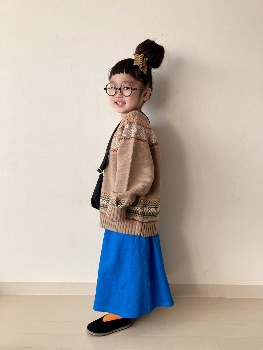 ベージュ系のニット/セーター、ブルー系のスカート、ブラック系のベストを着用したキッズの冬コーディネートの2枚目の写真