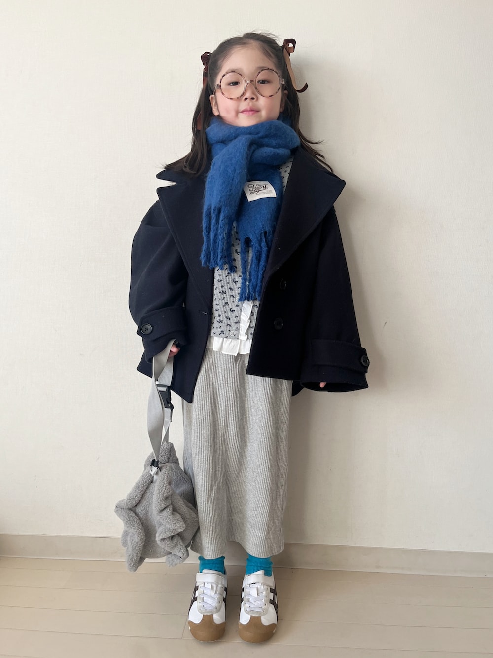グレー系のカーディガン/ボレロ、ブルー系のピーコート、グレー系のスカートを着用したキッズの秋コーディネートの4枚目の写真