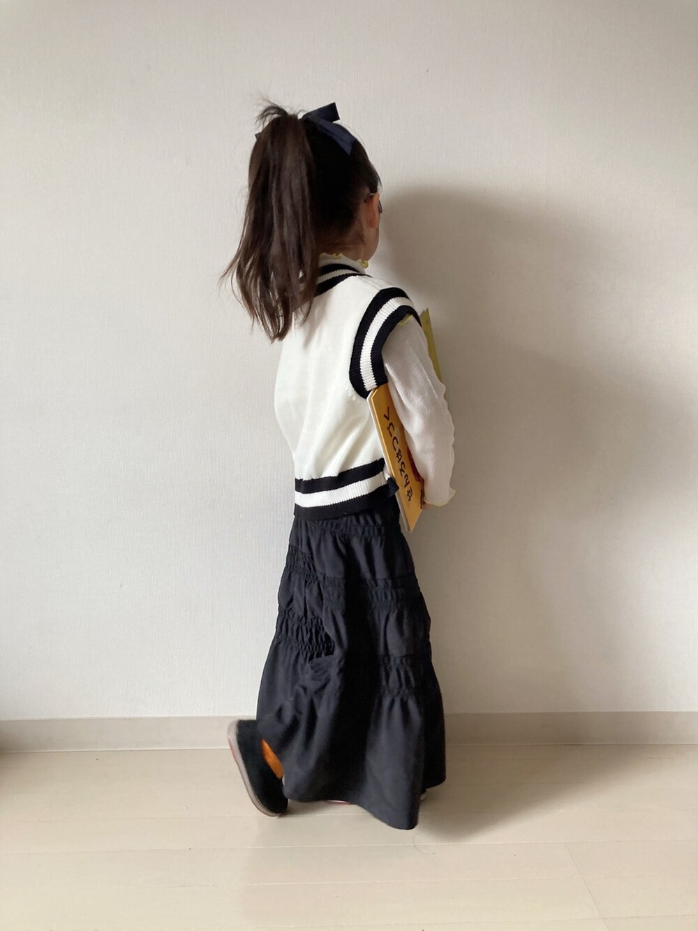 ブラック系のスカート、ホワイト系のTシャツ/カットソー、ホワイト系のベストを着用したキッズの冬コーディネートの4枚目の写真