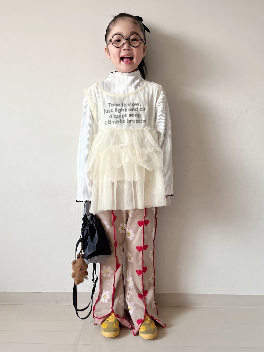 イエロー系のTシャツ/カットソー、ホワイト系のパンツ、ブラック系のショルダーバッグを着用したキッズの冬コーディネートの4枚目の写真