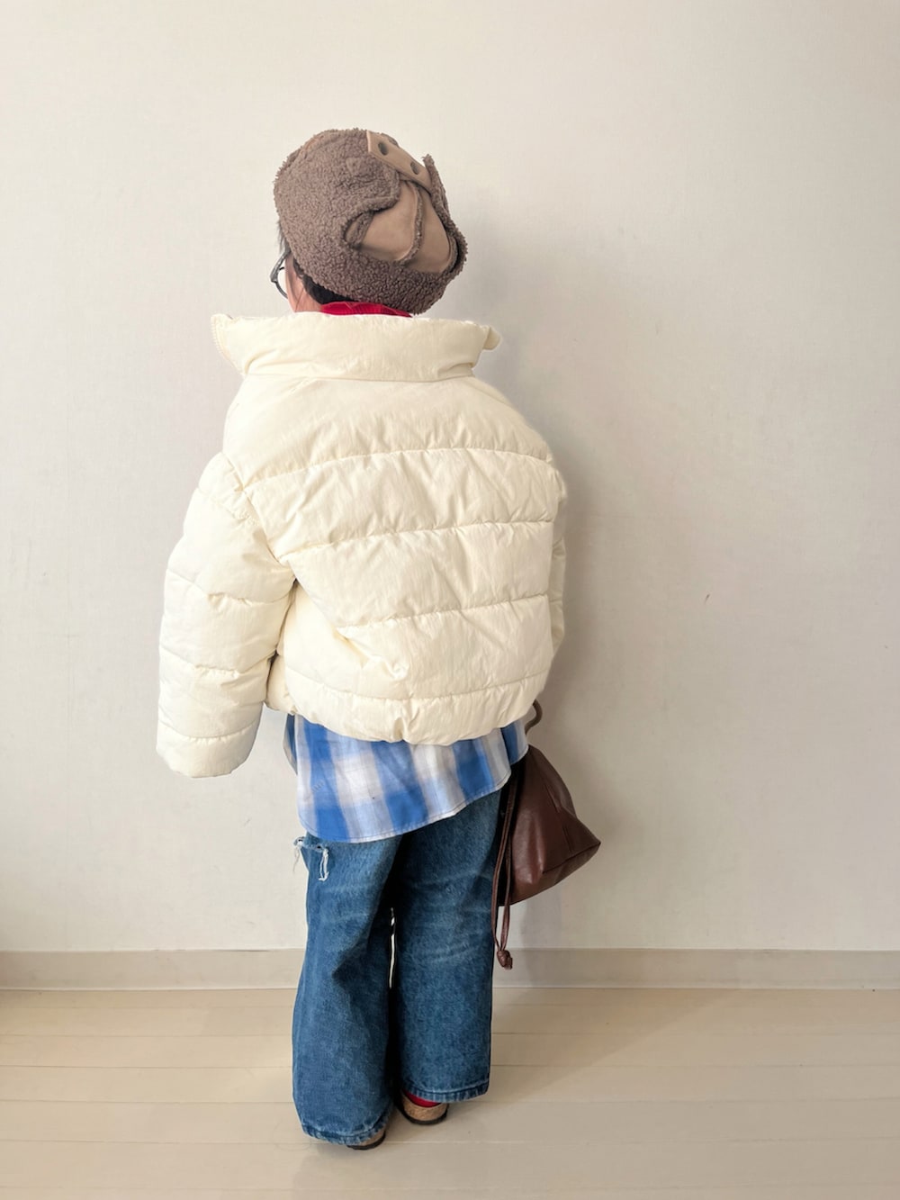 ホワイト系のダウンジャケット/コート、レッド系のTシャツ/カットソー、ブルー系のデニムパンツを着用したキッズの冬コーディネートの5枚目の写真