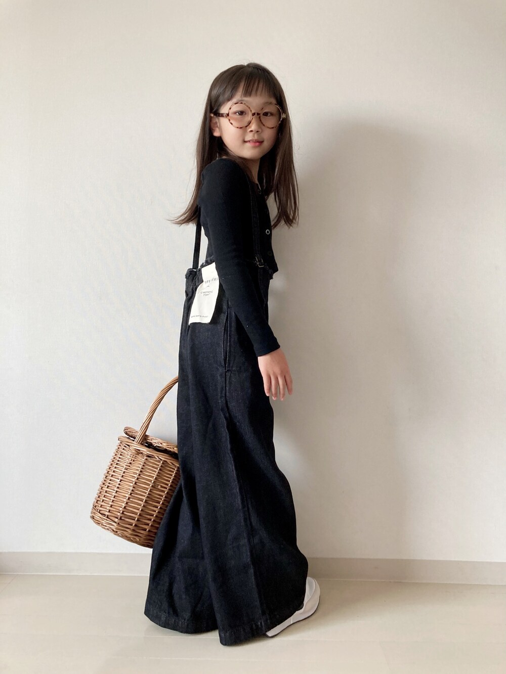 ブラック系のデニムパンツ、ホワイト系のスニーカー、ベージュ系のかごバッグを着用したキッズの夏コーディネートの4枚目の写真