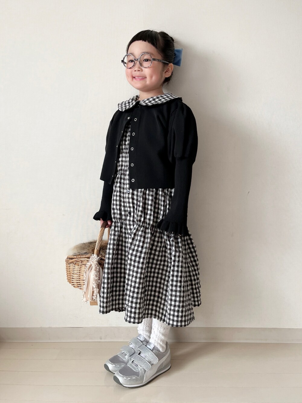 ブラック系のワンピース、ブラック系のカーディガン/ボレロ、ホワイト系のスニーカーを着用したキッズの冬コーディネートの2枚目の写真