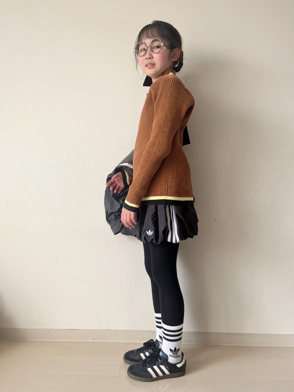 ブラック系のスカート、ブラウン系のニット/セーター、ブラック系のスニーカーを着用したキッズの冬コーディネートの4枚目の写真