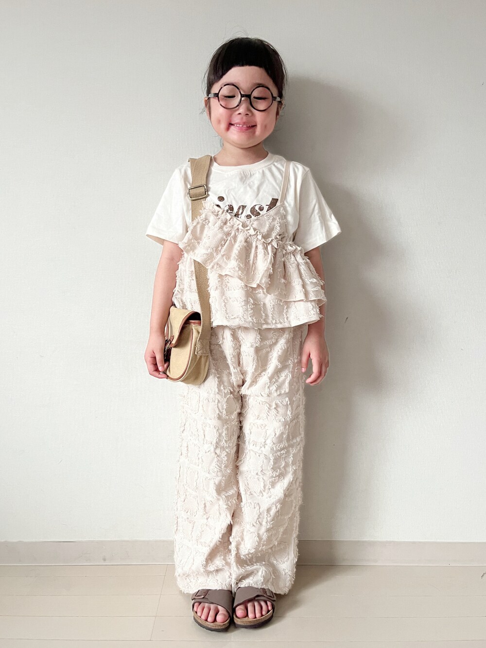 ベージュ系のショルダーバッグ、ブラウン系のサンダル、ベージュ系のTシャツ/カットソーを着用したキッズの春コーディネートの5枚目の写真