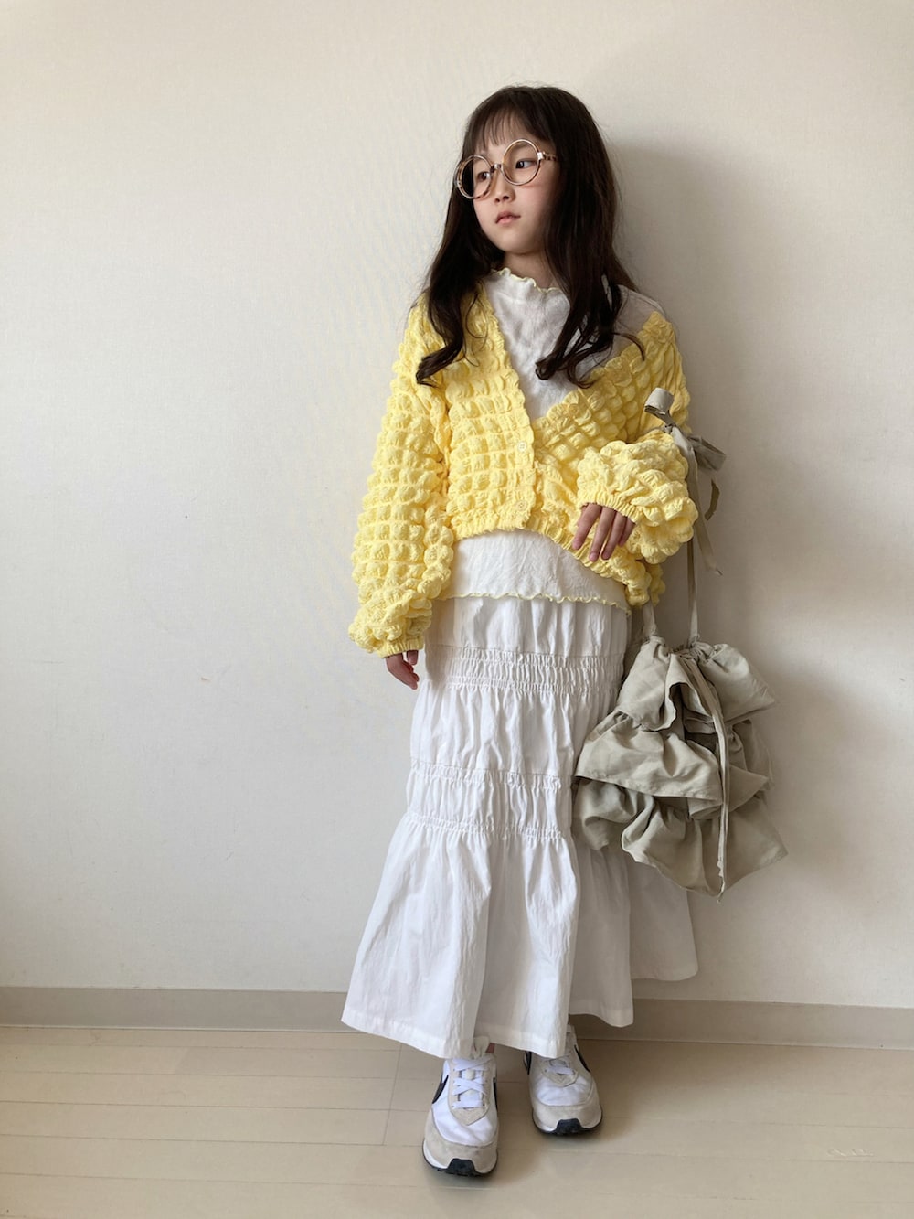 イエロー系のカーディガン/ボレロ、ホワイト系のTシャツ/カットソー、ホワイト系のスカートを着用したキッズの春コーディネートの3枚目の写真