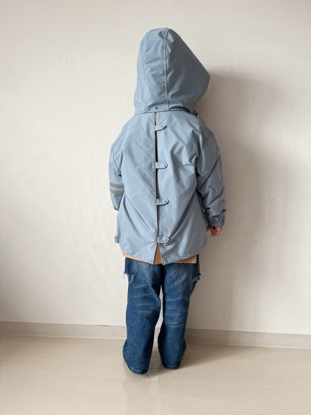 ブルー系のナイロンジャケット、オレンジ系のニット/セーター、ブルー系のデニムパンツを着用したキッズの秋コーディネートの5枚目の写真