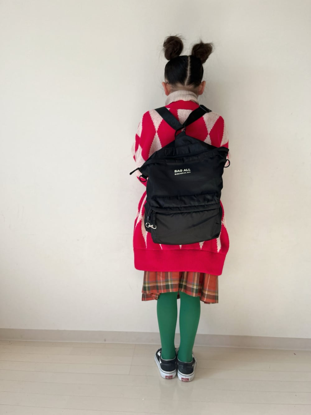 レッド系のカーディガン/ボレロ、レッド系のスカート、ブラック系のスニーカーを着用したキッズの冬コーディネートの3枚目の写真