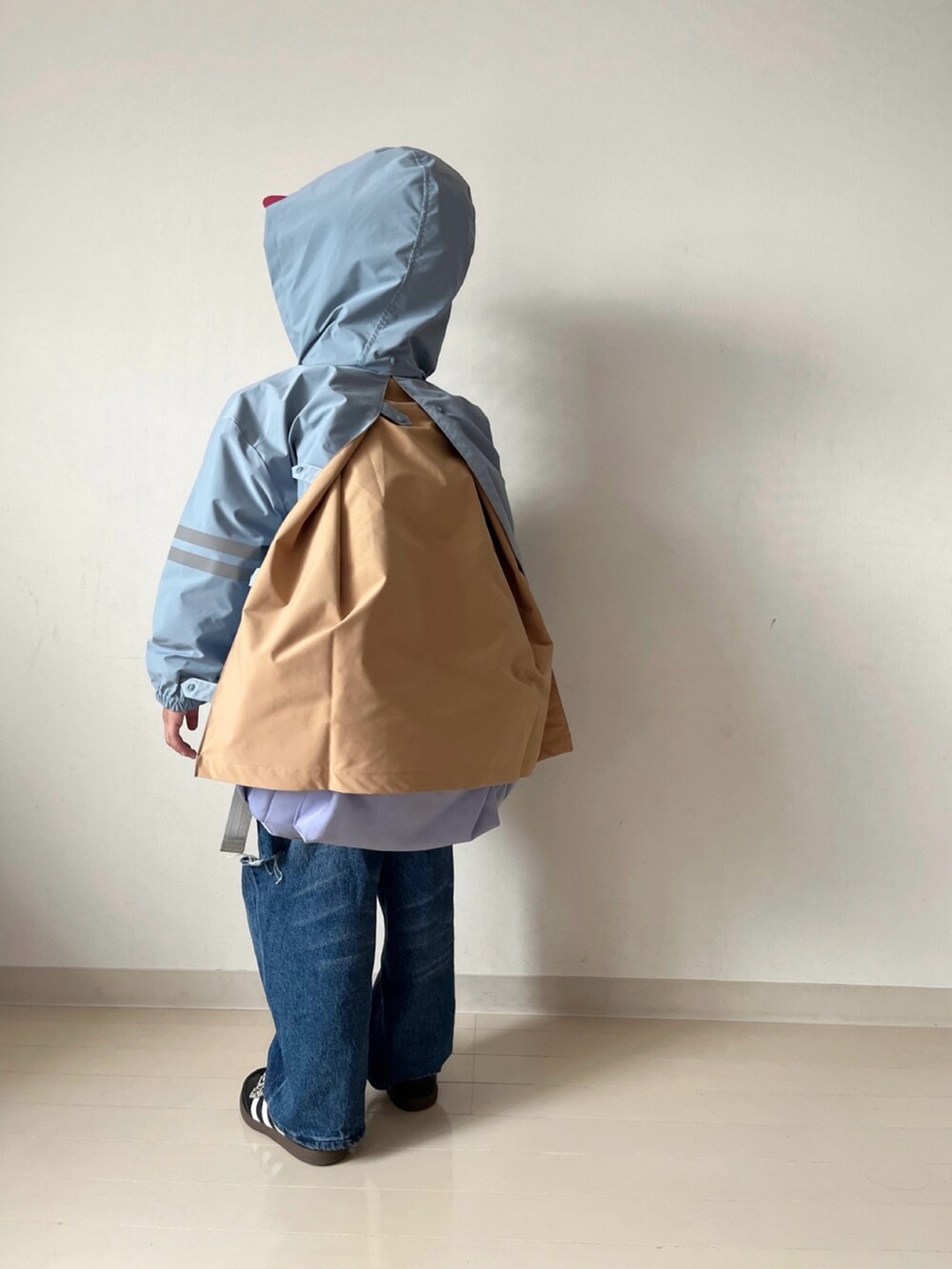 ブルー系のナイロンジャケット、オレンジ系のニット/セーター、ブルー系のデニムパンツを着用したキッズの秋コーディネートの4枚目の写真