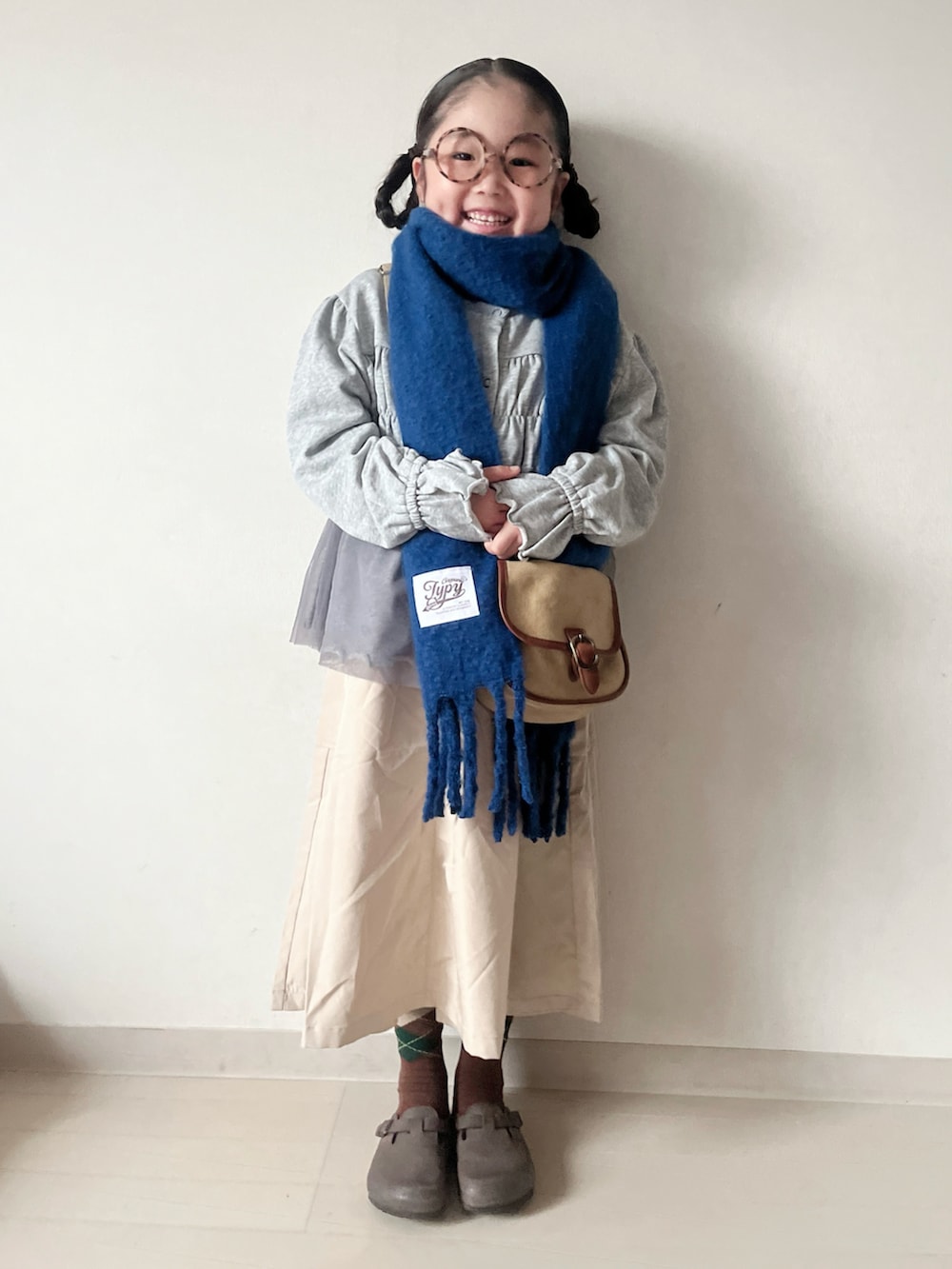 グレー系のカーディガン/ボレロ、ベージュ系のショルダーバッグ、ベージュ系のスカートを着用したキッズの秋コーディネートの4枚目の写真