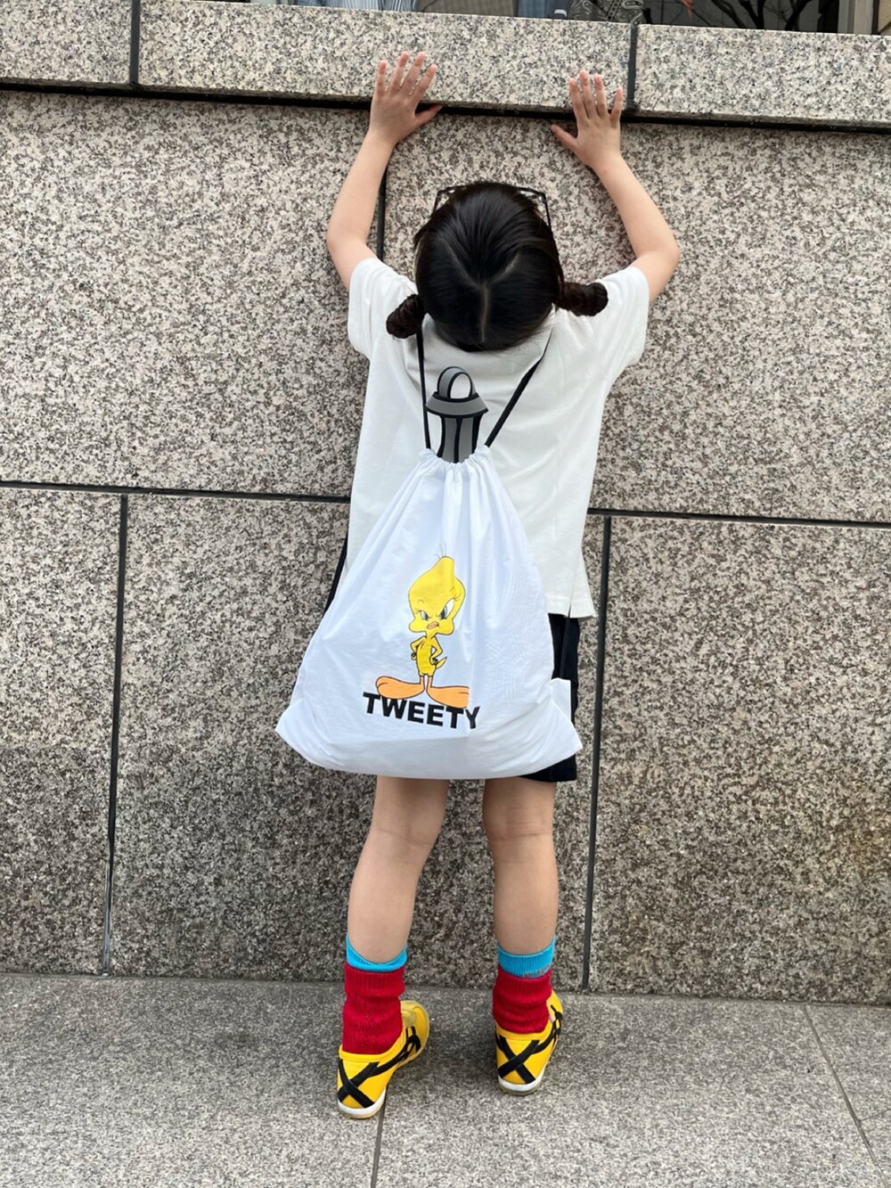ホワイト系のTシャツ/カットソー、ホワイト系のバックパック/リュック、イエロー系のスニーカーを着用したキッズの春コーディネートの3枚目の写真