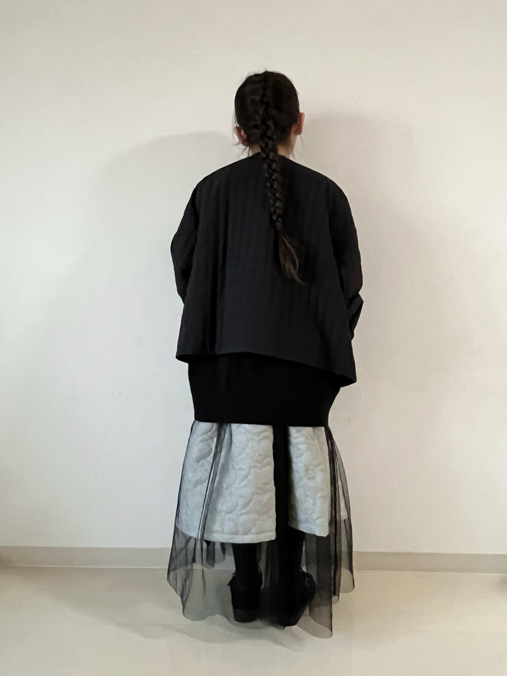 ブラック系のナイロンジャケット、ブラック系のニット/セーター、ホワイト系のスカートを着用したキッズの冬コーディネートの5枚目の写真