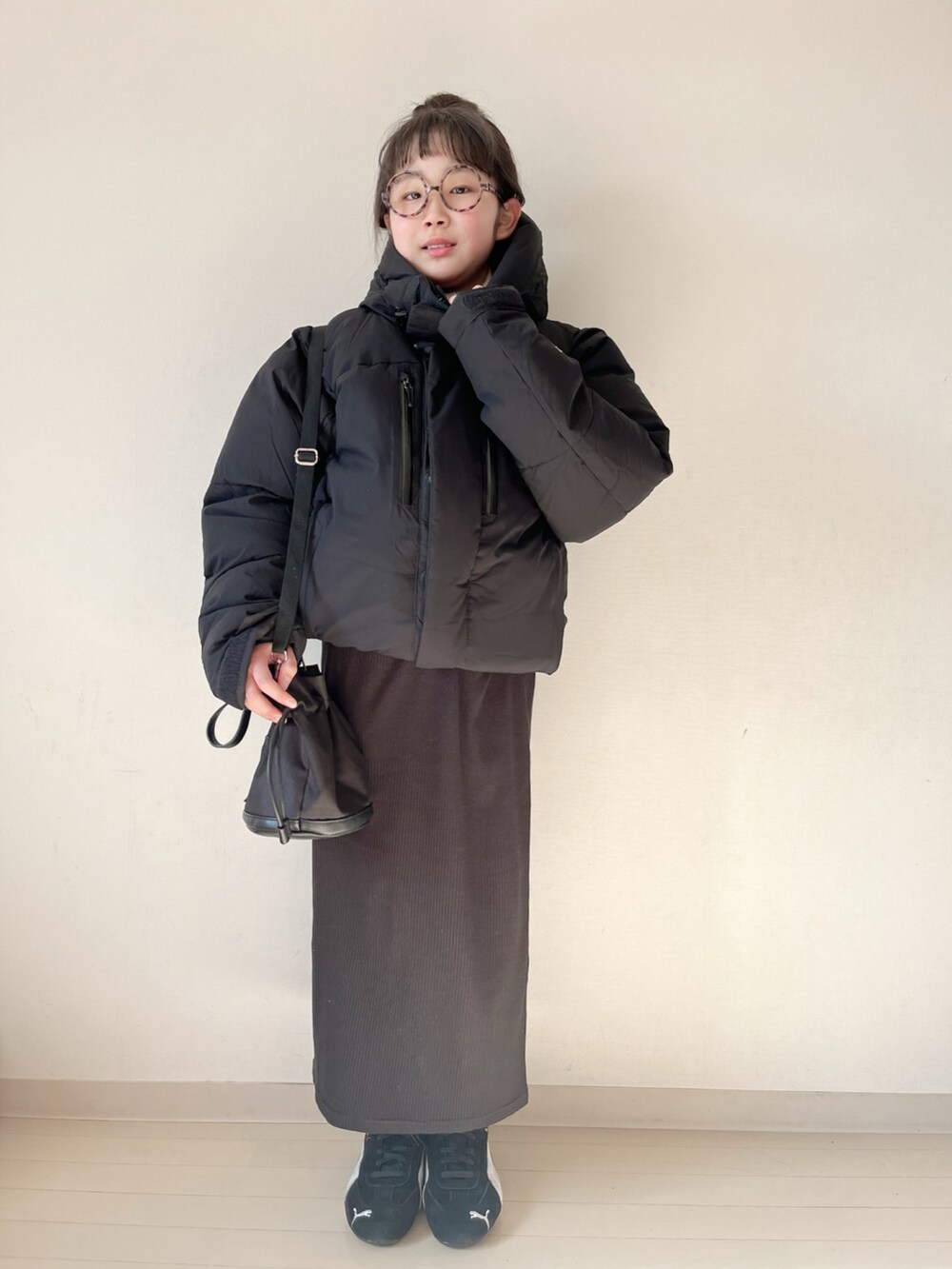 ブラック系のダウンジャケット/コート、ブラック系のスカート、ベージュ系のニット/セーターを着用したキッズの冬コーディネートの2枚目の写真