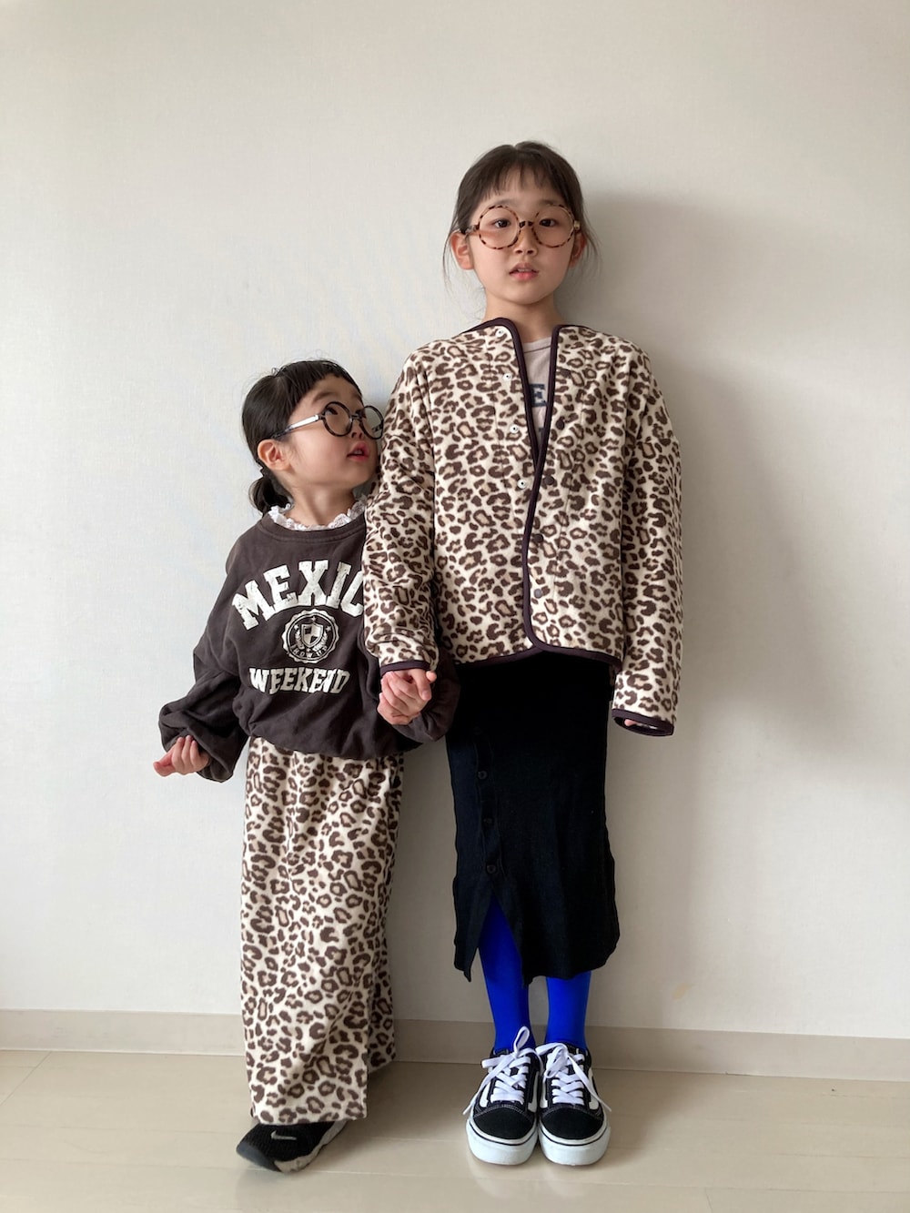 ベージュ系のカーディガン/ボレロ、ベージュ系のTシャツ/カットソー、ブラック系のスニーカーを着用したキッズの冬コーディネートの2枚目の写真