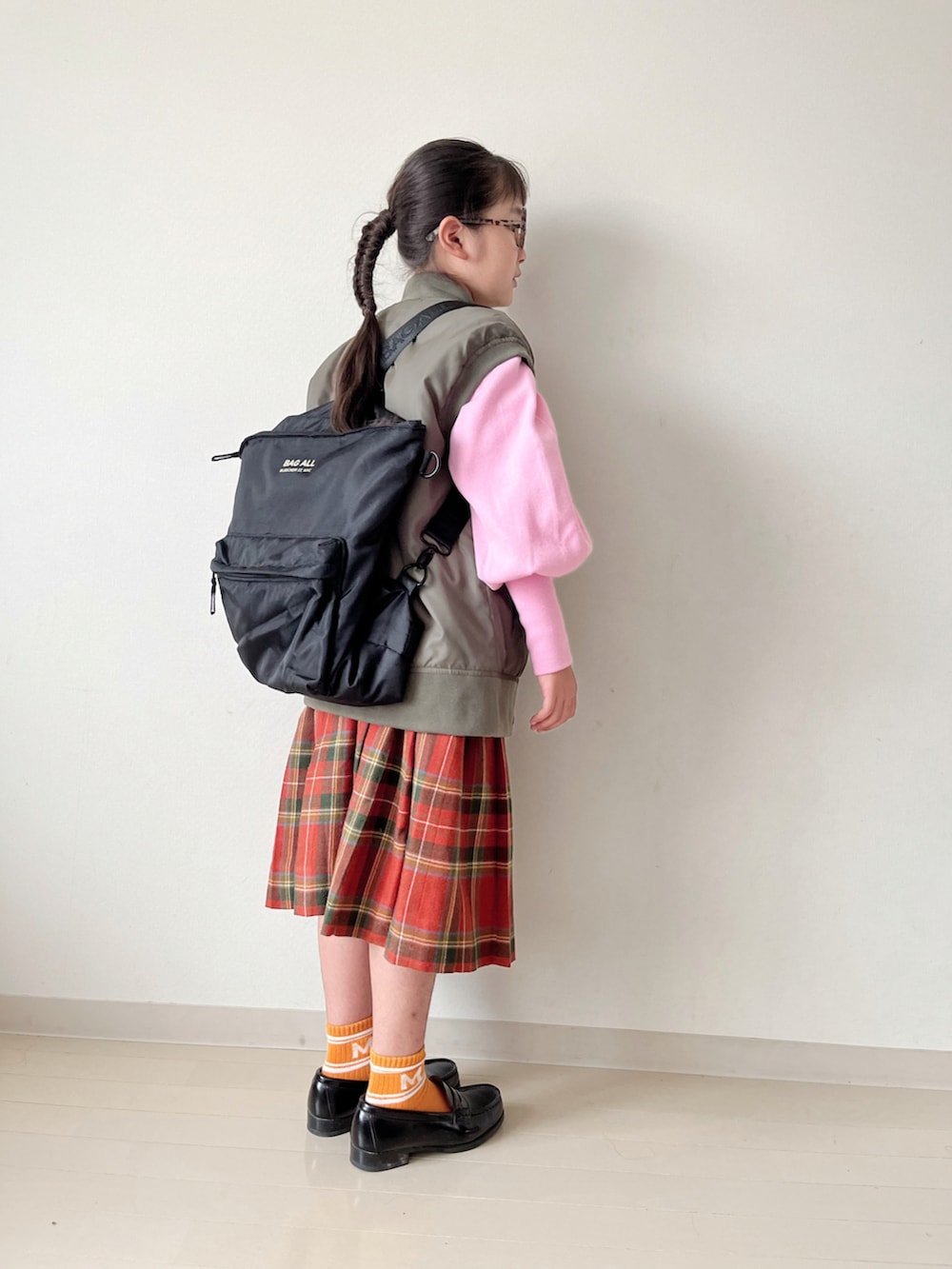 ピンク系のニット/セーター、グリーン系のダウンベスト、ブラック系のローファーを着用したキッズの秋コーディネートの2枚目の写真