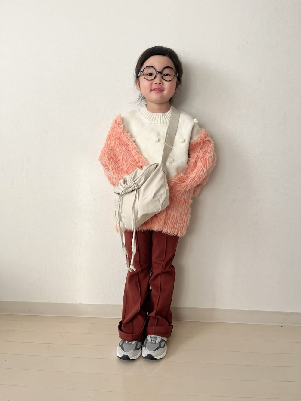 ホワイト系のニット/セーター、オレンジ系のカーディガン/ボレロ、グレー系のスニーカーを着用したキッズの秋コーディネートの3枚目の写真