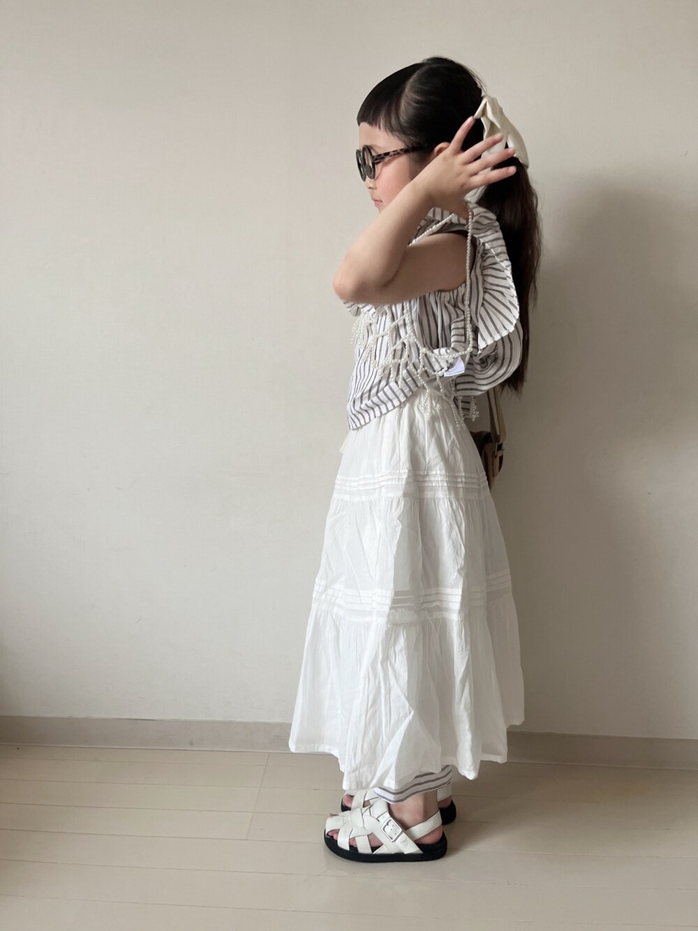 ホワイト系のスカート、ベージュ系のショルダーバッグ、ブラック系のセットアップを着用したキッズの夏コーディネートの3枚目の写真